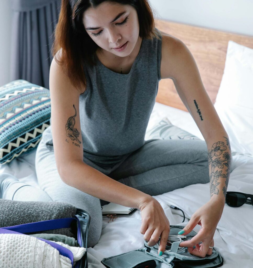 Woman sitting on a bed packing a  small bag.